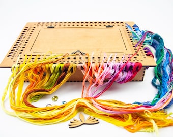 May include: A wooden cross-stitch kit with a rectangular frame and a variety of colorful embroidery floss. The floss includes shades of yellow, orange, pink, purple, and blue. Also included are small, decorative gems and a wooden cutout.