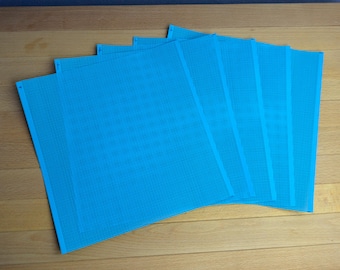 May include: A set of five rectangular sheets of bright blue plastic canvas, each featuring a uniform grid of small, evenly spaced holes. The sheets are arranged in a slightly overlapping, fanned-out formation, displaying their consistent texture.