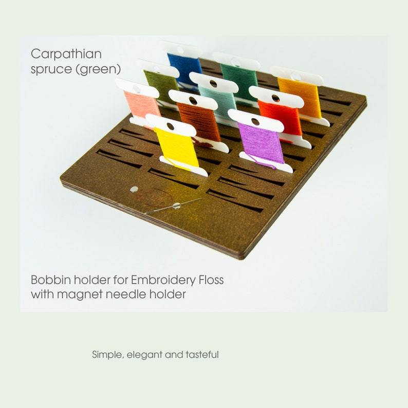 Op de afbeelding: Een houten bobbinhouder voor borduurgaren met een magnetische naaldhouder. De houder heeft 12 vakjes voor bobbins en een kleine magneet aan de zijkant voor naalden. De bobbins zijn gevuld met kleurrijk borduurgaren.