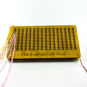 May include: A wooden embroidery thread organizer with numerous holes and numbers. The organizer has colorful threads attached and the text "I love to embroider with thread".