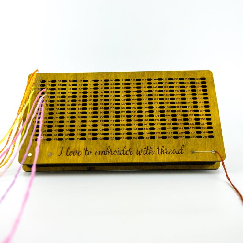 May include: A wooden embroidery thread organizer with numerous holes and numbers. The organizer has colorful threads attached and the text "I love to embroider with thread".