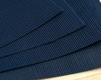 May include: A stack of dark navy blue rectangular sheets featuring a uniform, fine grid pattern of small, evenly spaced circular perforations across the entire surface. The sheets are layered at slight angles, revealing the consistent mesh texture.