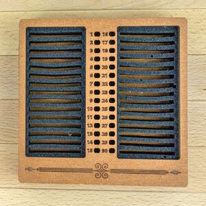 May include: A wooden calendar with 30 numbered slots, each separated by black foam. The numbers 1-30 are listed on the right and left sides. The calendar has a decorative design at the bottom.