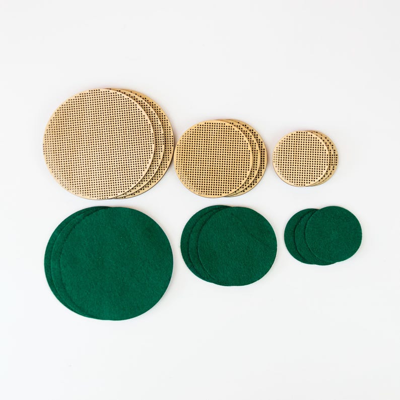 May include: A collection of craft supplies featuring wooden circles with a perforated design and dark green felt circles. The wooden circles are in varying sizes, and the felt circles are arranged in groups of two or three.