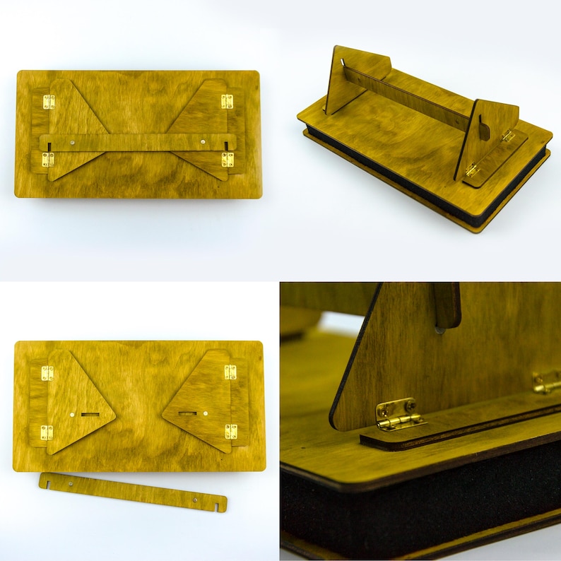 May include: A wooden laptop desk with a handle and folding legs. The desk is stained a golden yellow color and features brass hinges. The desk is designed to be portable and foldable for easy storage and use.