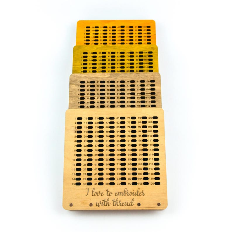 Op de afbeelding: Een houten borduurring met een raster van genummerde gaten. De ring is gemaakt van licht hout en heeft een natuurlijke afwerking. De tekst "Ik hou van borduren met draad" is gegraveerd op de onderkant van de ring.