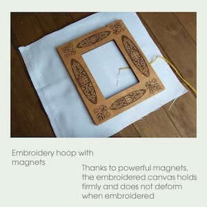 May include: A wooden embroidery hoop with a decorative design and powerful magnets to hold the canvas in place. The hoop is on a white canvas.