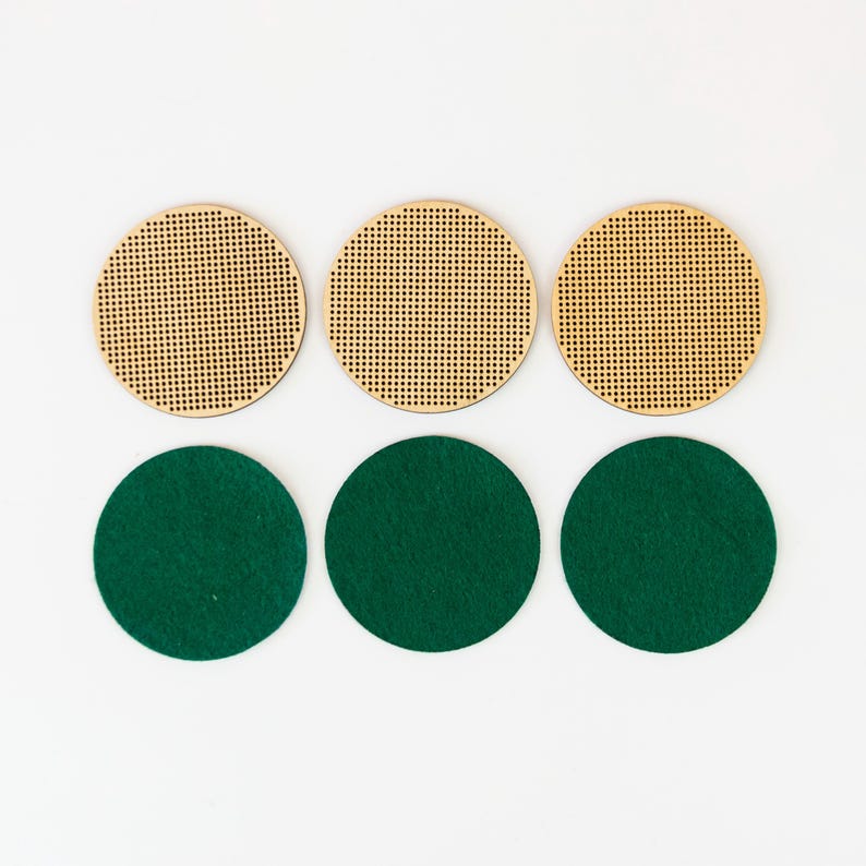 May include: Six round craft supplies: three wooden circles with perforated holes and three green felt circles. The wooden circles are light brown, and the felt circles are a deep green. The items are arranged in two rows of three.