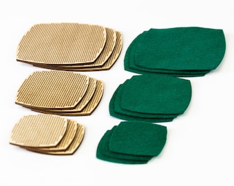 Op de afbeelding: Een assortiment houten en groene vilten onderzetters. De houten onderzetters zijn vierkant met afgeronde hoeken en een geperforeerd ontwerp. De groene onderzetters zijn effen en hebben een vergelijkbare vorm. Alle onderzetters zijn op een witte achtergrond geplaatst.