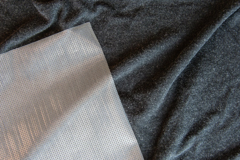 May include: A close-up of a gray fabric with a white mesh fabric overlay. The mesh fabric has a grid pattern.