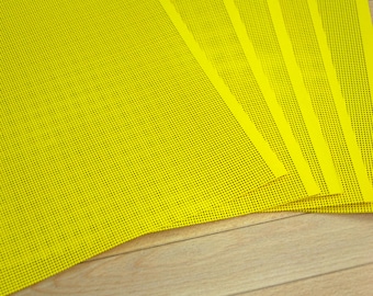May include: A stack of rectangular sheets of bright yellow plastic mesh, each featuring a uniform grid of small, evenly spaced circular perforations throughout the entire surface area, arranged in a slightly fanned-out overlapping pattern.