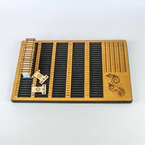 May include: A wooden multiplication board with slots for number tiles. The board has numbers from 1 to 125, with a decorative floral design on the right side. Several wooden number tiles are placed in the slots.