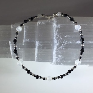 May include: A black and white beaded bracelet with silver accents. The bracelet is made with small round beads and features a mix of black and white stones.