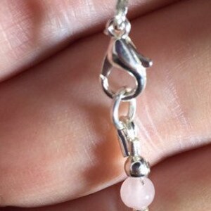 May include: A silver bracelet with alternating pink and black beads. The bracelet has a silver clasp.