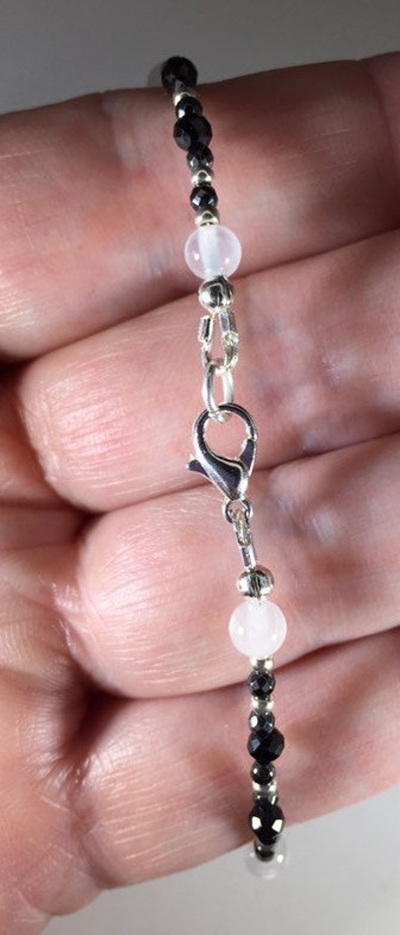 May include: A black and white beaded bracelet with a silver clasp. The bracelet features black faceted beads and white round beads.