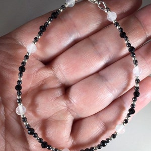 May include: A silver bracelet with black and white beads. The bracelet has a silver clasp.