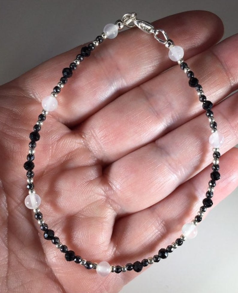 May include: A silver bracelet with black and white beads. The bracelet has a silver clasp.