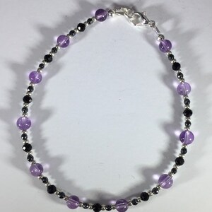 May include: A silver chain bracelet with alternating amethyst and black beads.