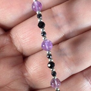 May include: A bracelet featuring alternating amethyst and black onyx beads. The bracelet is made with silver beads and is strung on elastic.