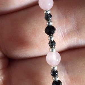 May include: A bracelet made with pink and black beads. The bracelet is made with alternating pink and black beads, with silver beads in between.