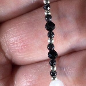 May include: A black and white beaded bracelet with silver spacers. The bracelet features alternating black and white beads.