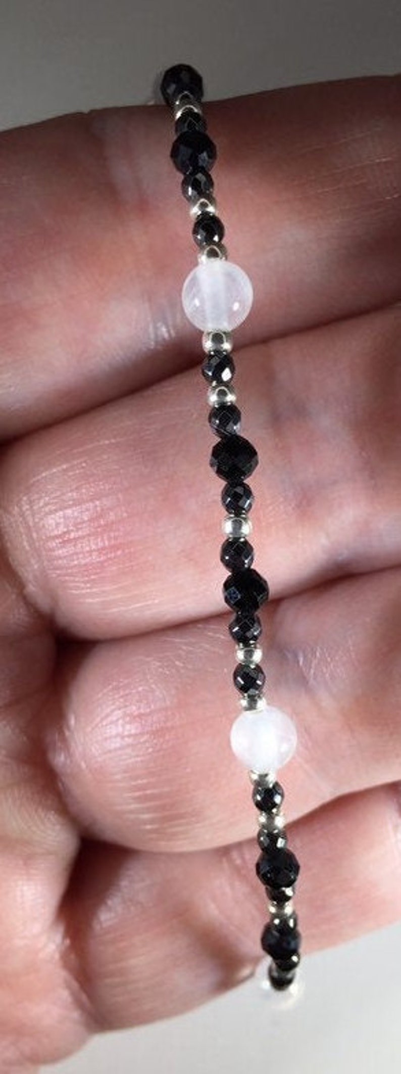 May include: A black and white beaded bracelet with silver spacers. The bracelet features alternating black and white beads.