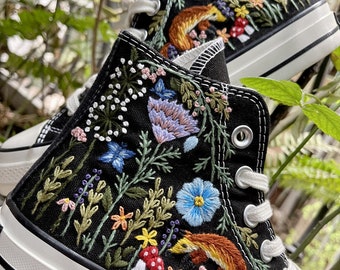 May include: Black high-top canvas sneakers with colorful embroidered flowers, leaves, mushrooms, and a fox.