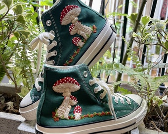 May include: A pair of green high-top canvas sneakers with white soles and red and white mushroom embroidery.