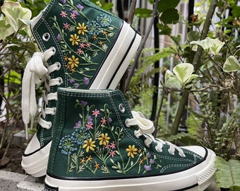 May include: Green high-top canvas sneakers with white soles and laces. The sneakers are embroidered with colorful flowers and greenery.