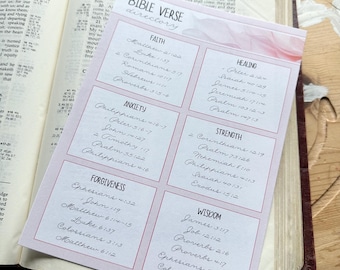 May include: Open Bible with a pink Bible verse directory card. The card lists verses under categories like Faith, Anxiety, and Healing. The text is handwritten in black ink on a pink background.