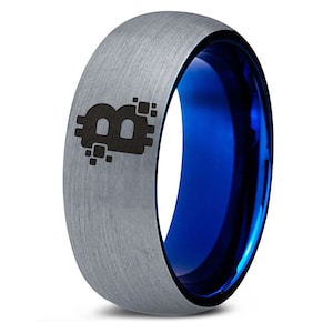 Op de afbeelding: Een zilveren ring van wolfraamcarbide met een blauwe binnenband en een zwart Bitcoin-symbool gegraveerd op de bovenkant.