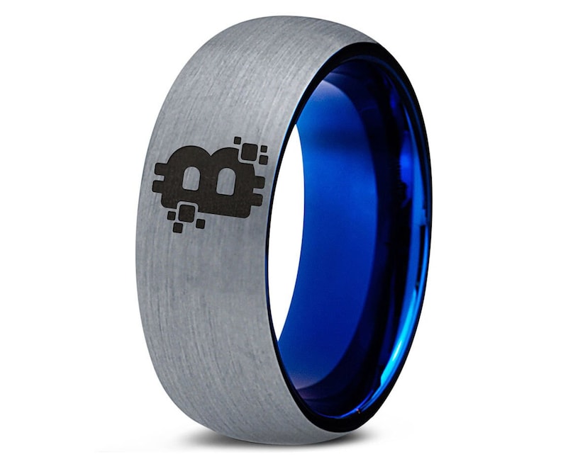 Op de afbeelding: Een zilveren ring van wolfraamcarbide met een blauwe binnenband en een zwart Bitcoin-symbool gegraveerd op de bovenkant.