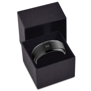 May include: A black ring with a brushed finish and a silver spider logo in a black ring box.