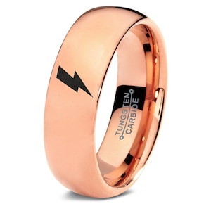 May include: A rose gold tungsten carbide ring with a black lightning bolt design. The ring is engraved with "TUNGSTEN CARBIDE" on the inside.