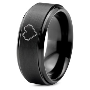 May include: A black tungsten carbide ring with a beveled edge and a pixelated heart design.