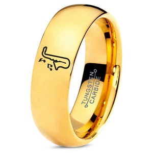 May include: Gold tungsten carbide ring with a saxophone and musical notes engraved on the band. The inside of the band is engraved with "TUNGSTEN CARBIDE".