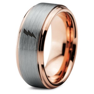 May include: A silver and rose gold tungsten carbide ring with a brushed finish and a lightning bolt design.
