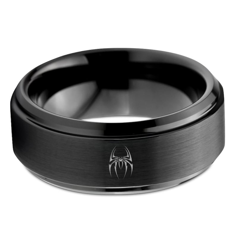 May include: A black tungsten carbide ring with a brushed finish and a black spider design engraved on the band.