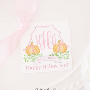 May include: A white card with a pink monogram and two watercolor pumpkins. The card has a pink ribbon with the text "Love, Hannah" and "Happy Halloween!"