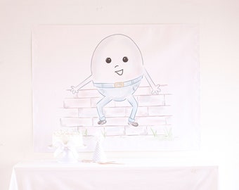 Puede incluir: Un fondo blanco con una mesa blanca cubierta con un mantel blanco con volantes. En la mesa hay un pastel blanco y un gorro de fiesta blanco. Detrás de la mesa hay un póster blanco con un dibujo animado de un huevo blanco con un cinturón azul y pantalones vaqueros azules, sentado en un muro de ladrillos.