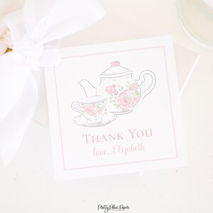 May include: A white thank you card with a pink border. The card features a pink and white teapot and teacup with floral designs. The text on the card reads "Thank You love, Elizabeth".