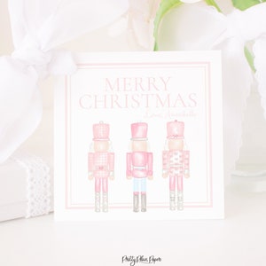 May include: A pink Christmas card with the text "Merry Christmas" and the name "Lanie Annabelle" in pink script. Three pink nutcracker figures are at the bottom of the card.