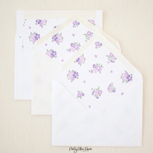 Pode incluir: Três envelopes brancos com um padrão floral roxo na aba interna. Os envelopes estão empilhados um em cima do outro. O envelope inferior tem o texto "Pretty Plain Paper" impresso na parte inferior.