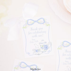 May include: Blue and white tea party thank you tags with a teapot, teacup, and floral designs. The text reads "Thank you for celebrating with me! love, Linny Belle".