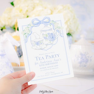 May include: A blue and white tea party invitation with a teapot, teacup, and flowers. The invitation says "Please join us for a Tea Party for Anderson Ann's 6th Birthday, Sunday, August 22nd at 1 o'clock in the afternoon, 111 First Street, Georgetown, KY".