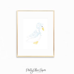 May include: A framed watercolor print of a white goose wearing a blue bonnet and shawl with a floral pattern. The goose has a yellow beak and feet. The print is in a gold frame, and the words "Pretty Plain Paper" are at the bottom.