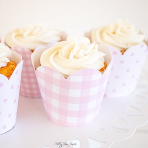 May include: Four cupcakes with white frosting and pink and white polka dot and gingham cupcake liners. The cupcakes are on a white doily.