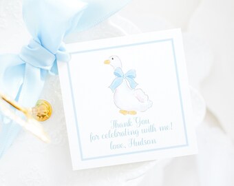 May include: A blue and white thank you tag with a watercolor illustration of a goose wearing a blue bow. The text reads "Thank You for celebrating with me! love, Hudson".