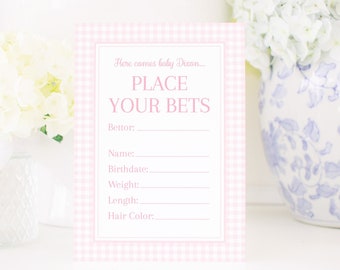 May include: Pink and white gingham baby shower game card with the text "Here comes baby Dixon... Place Your Bets". The card has spaces to fill in the bettor's name, birthdate, weight, length, and hair color.