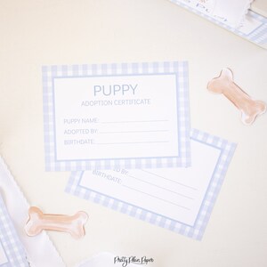 May include: A blue and white gingham puppy adoption certificate with the text "PUPPY ADOPTION CERTIFICATE" and spaces for the puppy's name, adopted by, and birthdate.